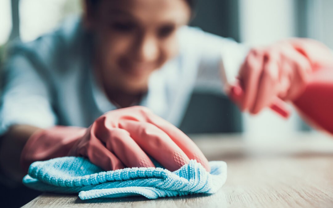 A Housekeeper Wearing Gloves While Wiping Off and End Table